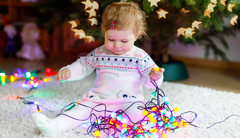 toddler playing with string of colorful lights 